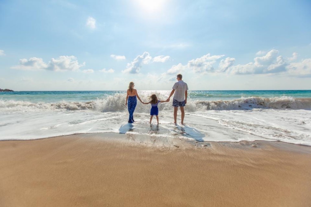 A family walking on a beach, shown full-screen in a frame