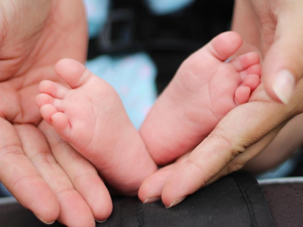 A newborn's feet held in a parent's hands, framed